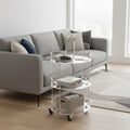 3-tier clear acrylic rolling cart styled in a bright living room, with a vase and decor on top, books on the middle shelf, and a storage basket on the bottom