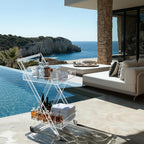 Acrylic rolling bar cart on a luxury outdoor patio overlooking the ocean