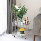Clear acrylic bar cart styled with flowers and copper barware in a modern living space