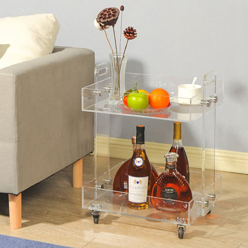 Clear acrylic bar cart holding liquor bottles and fruit, styled next to an armchair