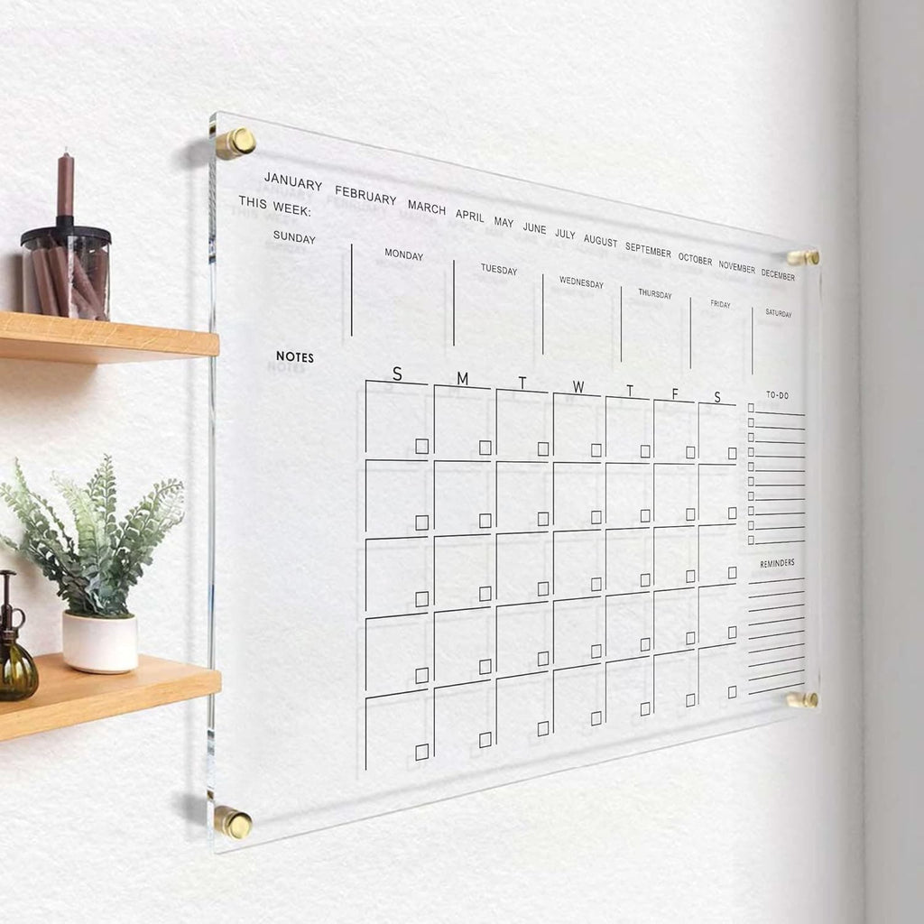 Clear acrylic wall calendar mounted in a minimalist hallway with wooden shelves