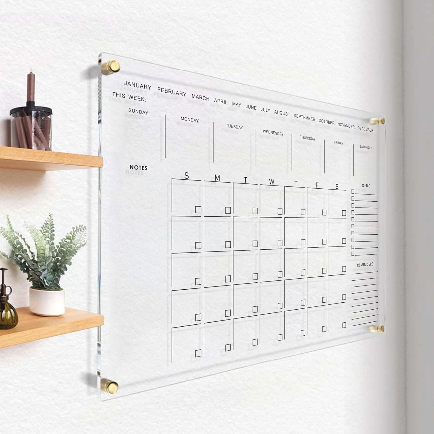 Clear acrylic wall calendar mounted in a minimalist hallway with wooden shelves