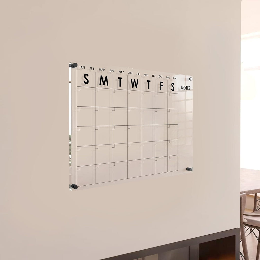Minimalist clear acrylic monthly planner mounted on a neutral wall, showcasing sleek design