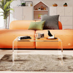 Clear acrylic coffee table in a vibrant living room with an orange sofa, demonstrating its ability to blend with bold decor