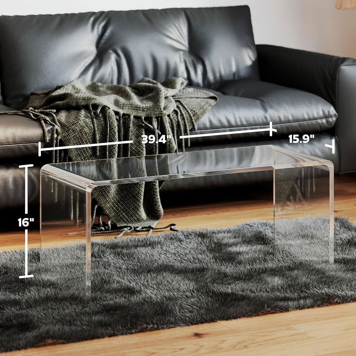 Dimension diagram of the acrylic waterfall coffee table: 39.4" x 15.9" x 16", shown next to a black leather sofa for scale