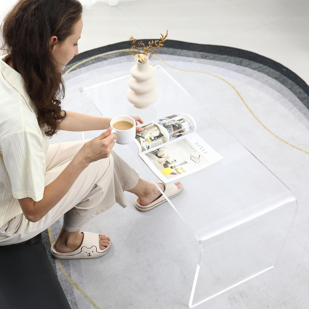 Top-down view of the acrylic coffee table, styled with a coffee cup, magazine, and vase, showcasing its reflective surface
