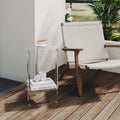 2-tier acrylic corner side table next to a modern lounge chair, holding a coffee cup and books