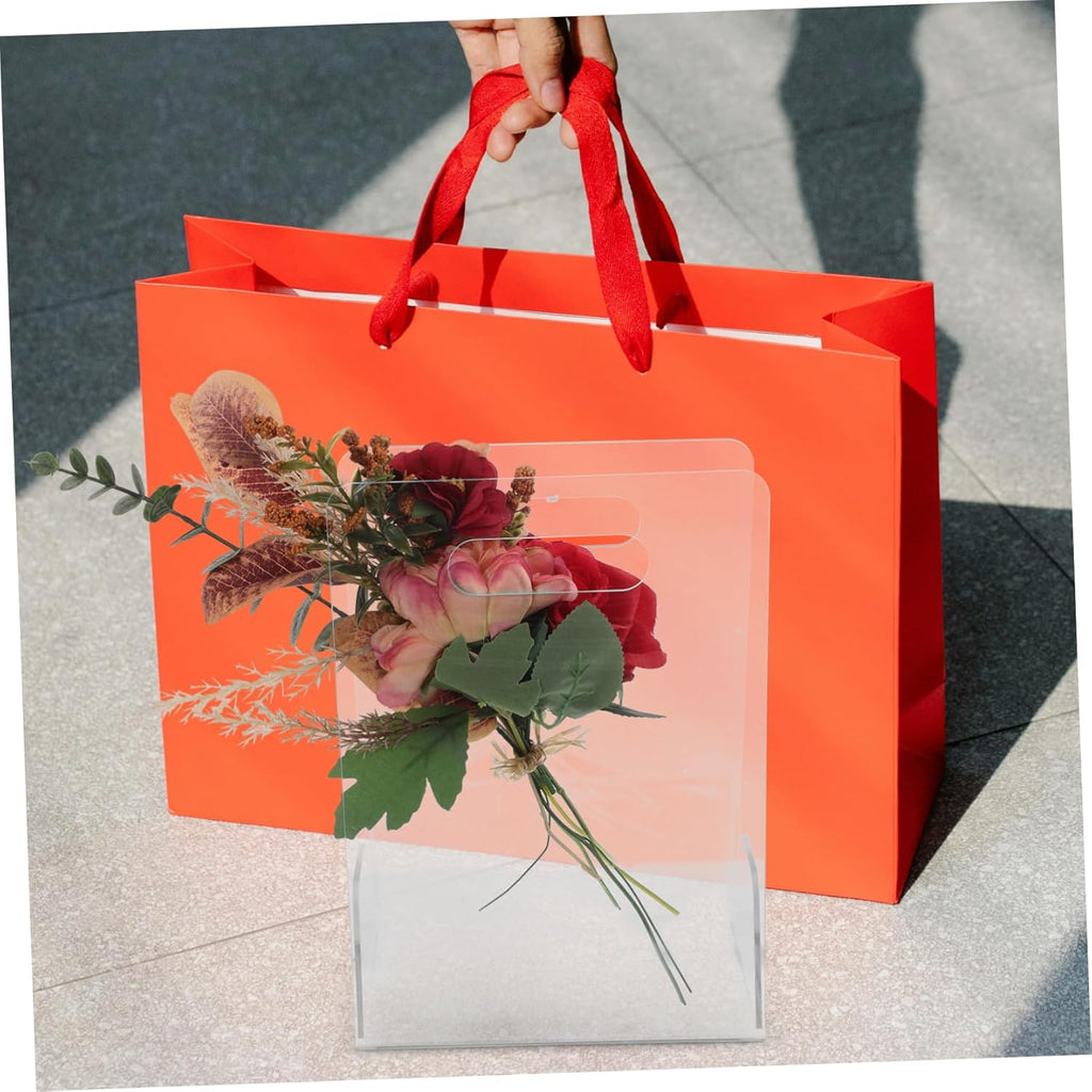 Clear acrylic flower box with a bouquet, paired with a bright orange gift bag for gifting