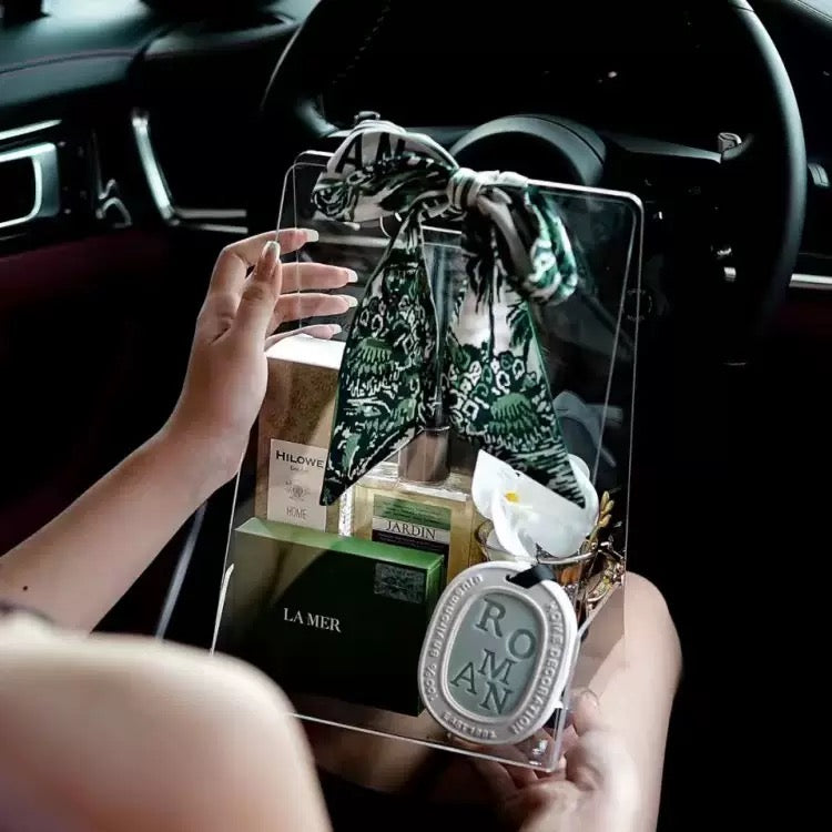 Clear acrylic handheld box used as a luxury gift bag, filled with premium skincare products