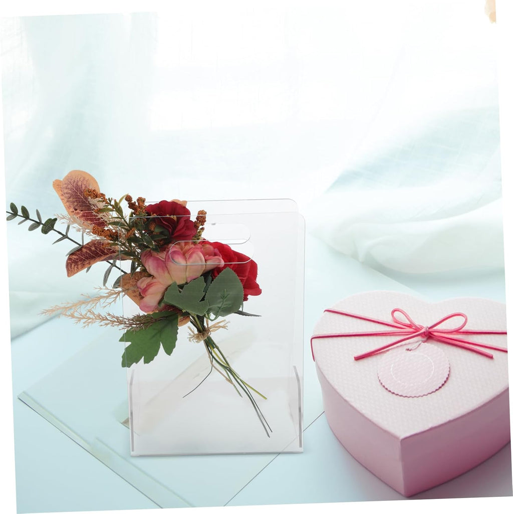 Clear acrylic flower box with a bouquet, next to a pink heart-shaped gift box