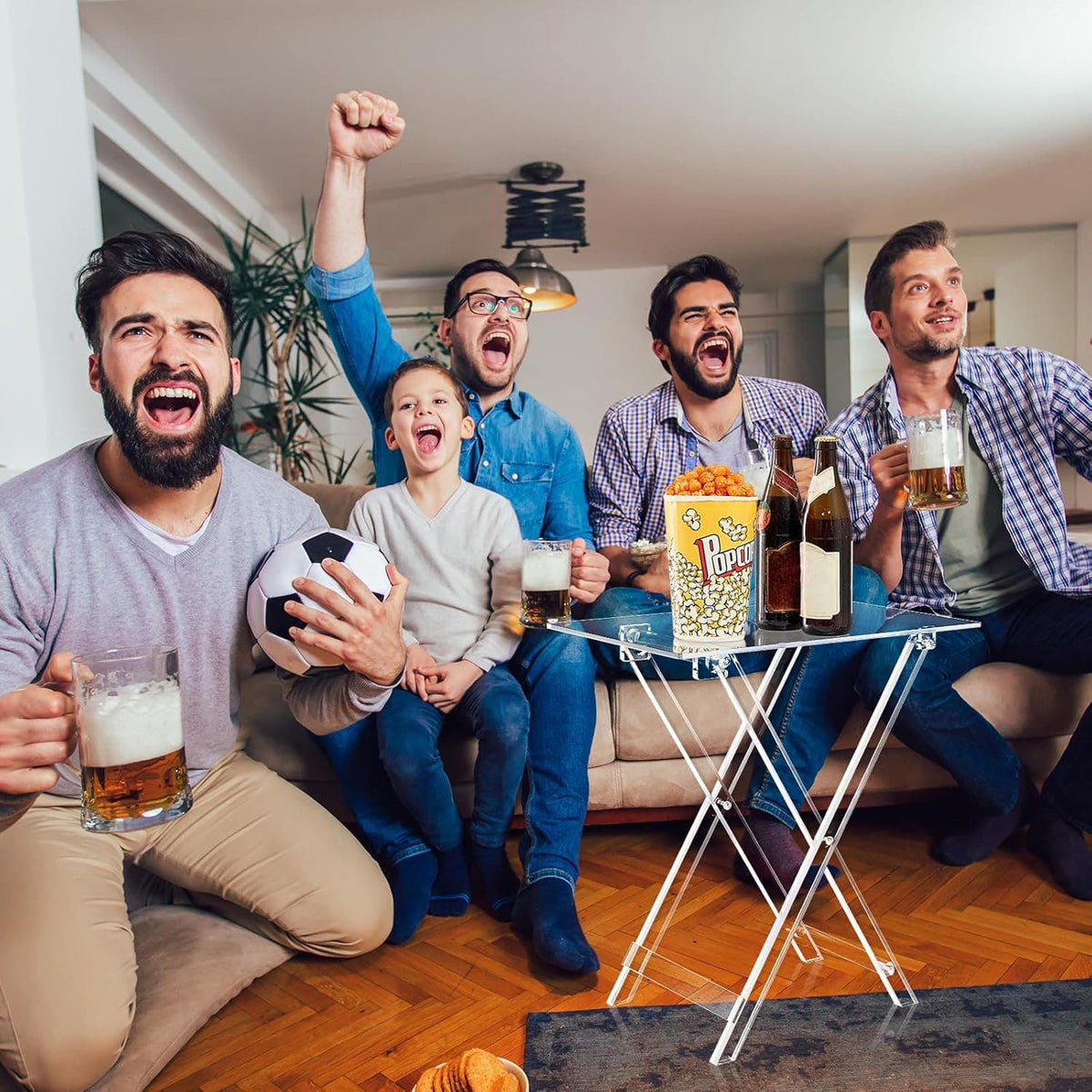 Acrylic foldable table used as a snack station during a game night, holding popcorn and drinks for a group of friends