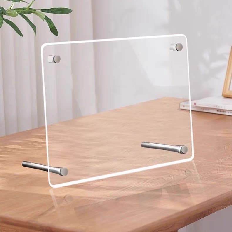 Clear acrylic frame with detachable metal stand accessories, placed on a wooden table