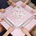 4 clear acrylic mahjong racks with magnetic pushers on pink table, playing American mahjong game scene, tiles for demo only