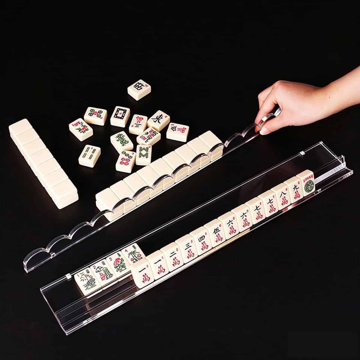Hand demo using magnetic acrylic mahjong pusher on clear scalloped mahjong rack, mahjong tiles for demonstration only, black background
