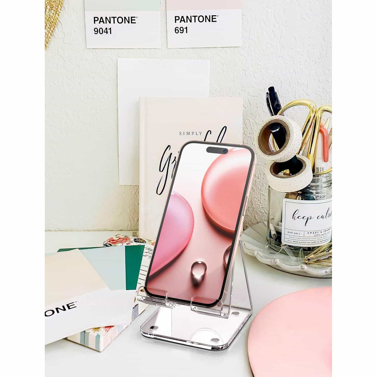 Clear acrylic phone stand styled on a vanity desk with stationery and decor, blending functionality and aesthetics