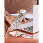 Clear acrylic phone stand holding an iPhone on a desk next to a laptop, ideal for home offices