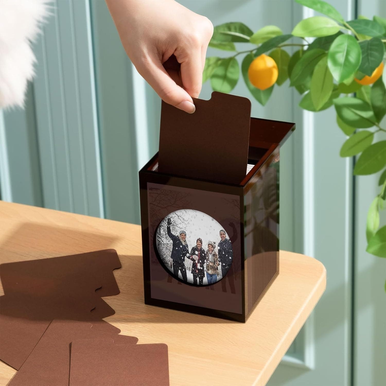 Hand pulling a photo card from the acrylic box, demonstrating easy access to stored photos/cards
