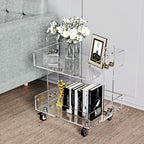 Clear acrylic rolling cart used as a side table in a living room, holding decor and books