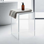 Transparent acrylic bench with towel and soap dispenser placed by a contemporary bathtub