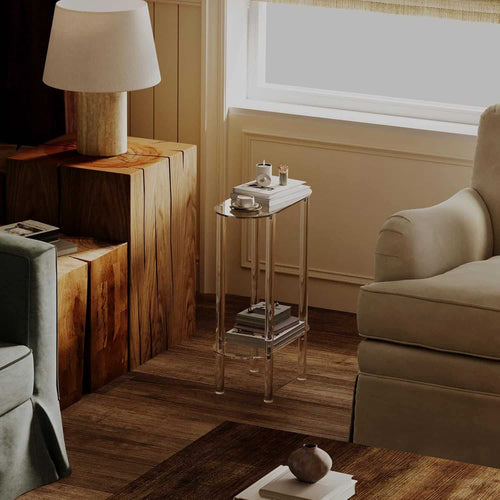 2-tier acrylic side table placed next to a beige armchair, holding a mug and books