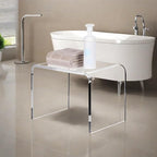 Transparent acrylic bench with towels and soap dispenser placed by a modern freestanding tub