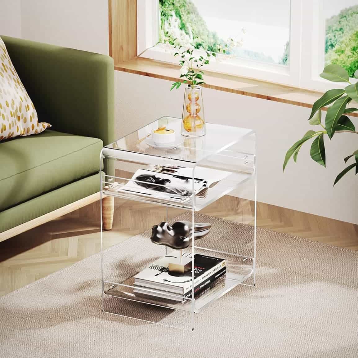 3-tier clear acrylic side table paired with a green sofa, styled with a vase of plants and coffee cup