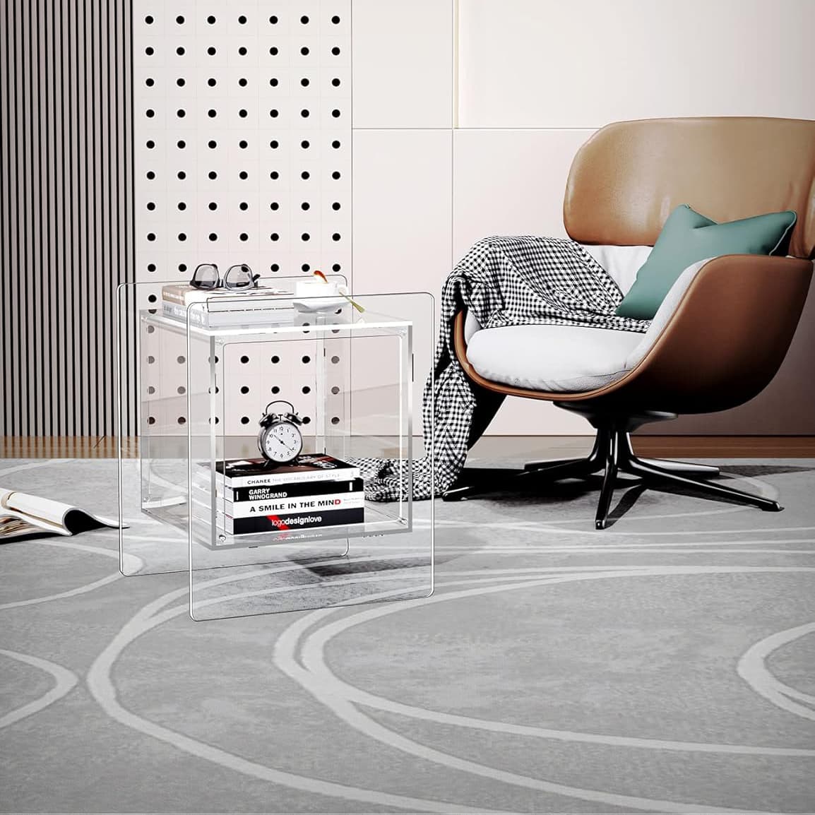 Clear acrylic cube side table in a modern reading nook, paired with a leather armchair and checkered throw