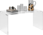 Clear acrylic waterfall coffee table styled with headphones, books, and a drink set, highlighting its sleek, transparent design