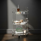 Elegant 3-tier acrylic bar cart used as a drink station, with a bottle of liquor, glasses, and accessories arranged across its shelves